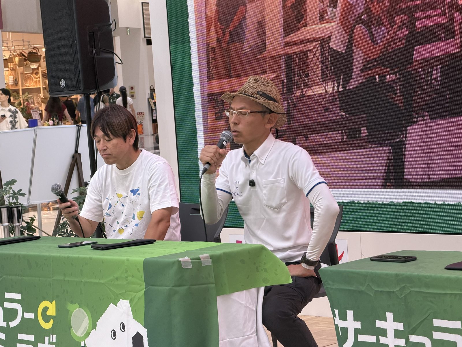 ステージのテーブルで、マイクを手に話す畔上順平さんと石野剛史さん