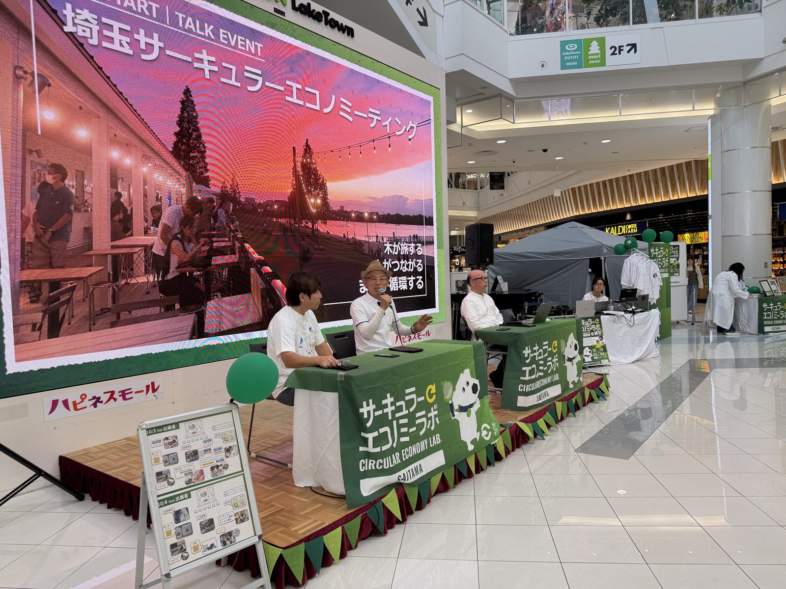 ステージを横から見た会場。手前に出展者マップの看板、奥に出展ブースのテントが並ぶ